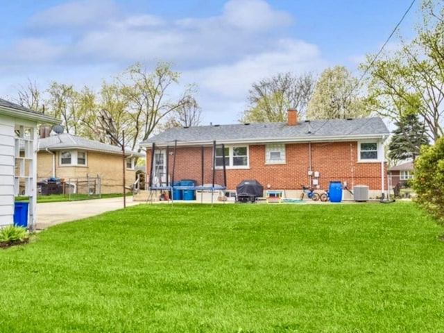 rear view of house featuring central AC and a lawn