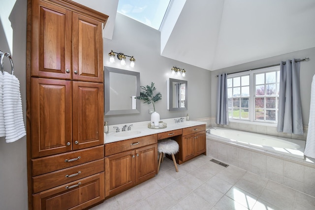 bathroom featuring tile patterned flooring, vanity, a relaxing tiled tub, and vaulted ceiling