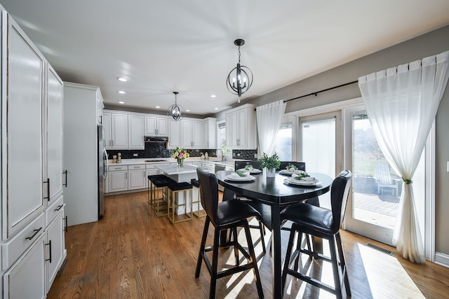 dining space with dark wood-type flooring, sink, and an inviting chandelier