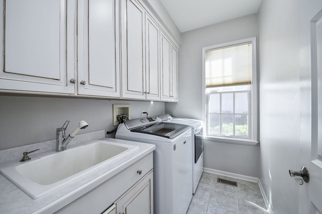 washroom with sink, light tile patterned floors, washing machine and dryer, and cabinets