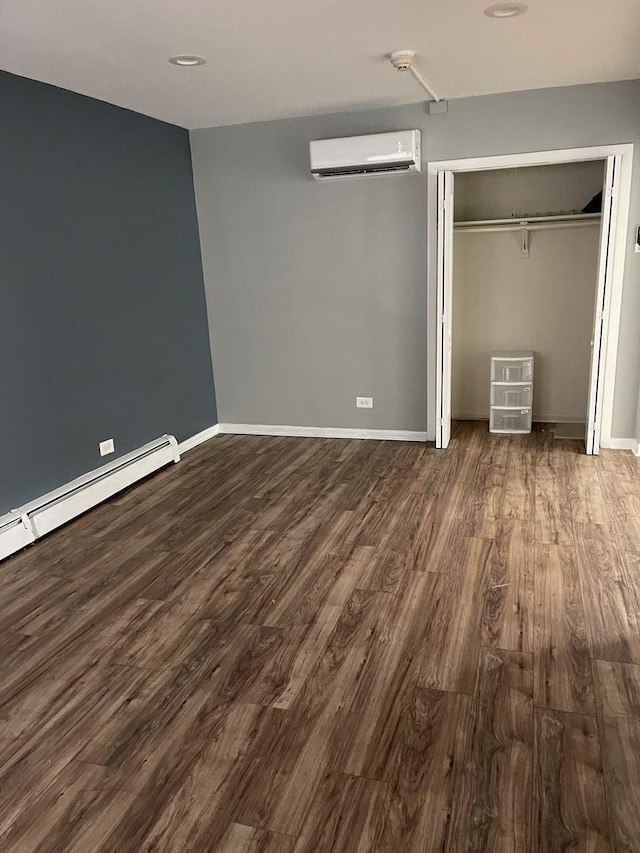 unfurnished bedroom with dark wood-type flooring, a closet, baseboard heating, and a wall unit AC