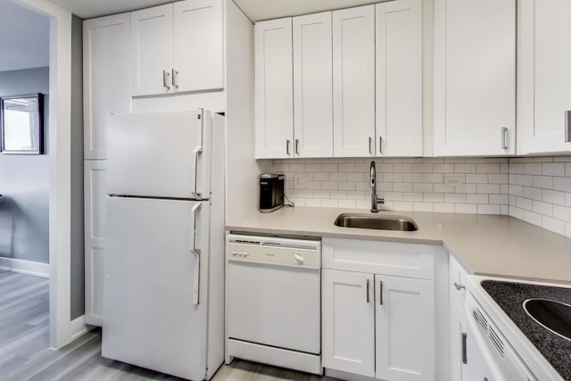 kitchen with sink, white appliances, light hardwood / wood-style flooring, backsplash, and white cabinets