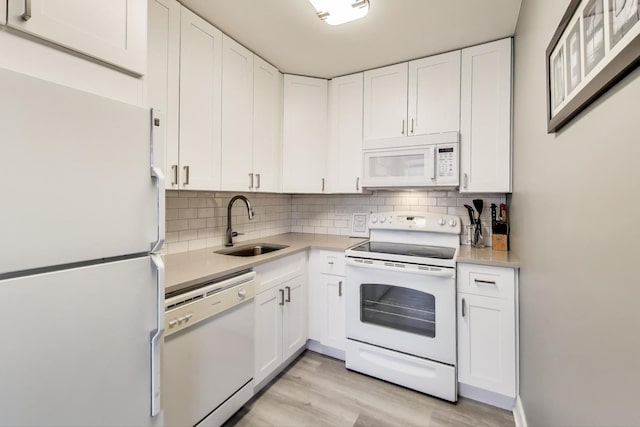 kitchen with sink, white cabinetry, white appliances, light hardwood / wood-style floors, and backsplash