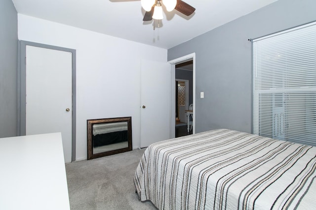 bedroom featuring ceiling fan, light colored carpet, and a fireplace