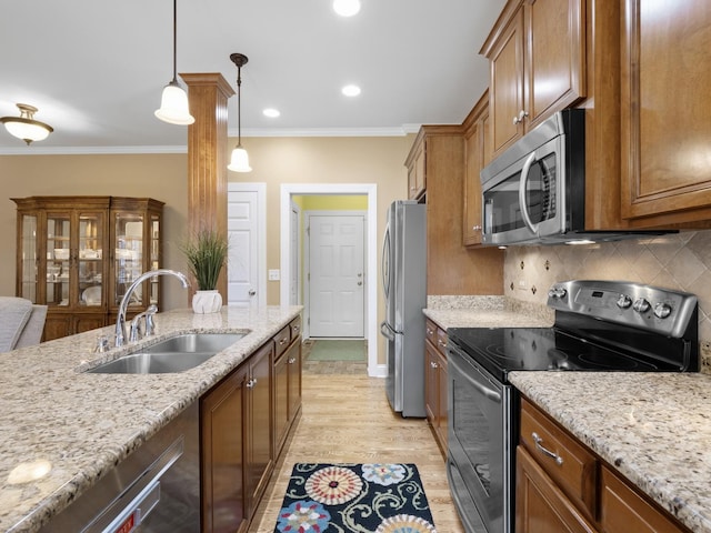 kitchen with sink, crown molding, pendant lighting, stainless steel appliances, and light stone countertops