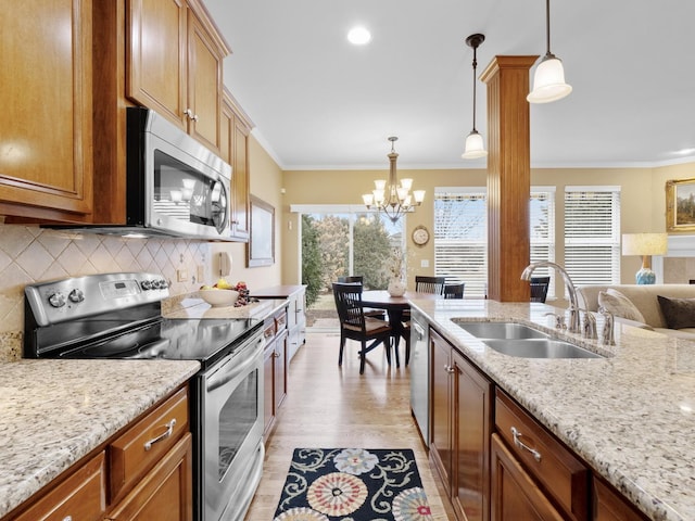 kitchen with sink, crown molding, decorative light fixtures, stainless steel appliances, and light stone countertops