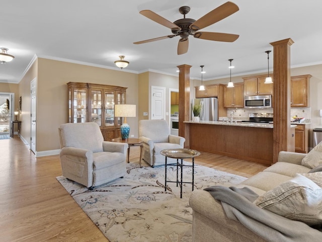 living room featuring sink, ornamental molding, ceiling fan, and light wood-type flooring