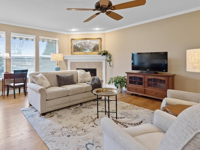 living room with a tiled fireplace, ornamental molding, and light hardwood / wood-style floors