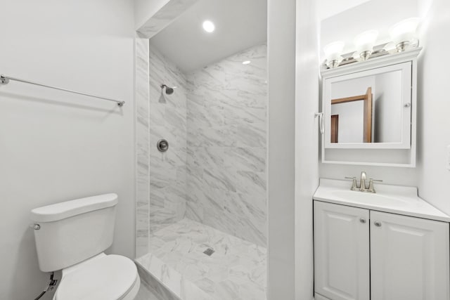 bathroom with tiled shower, vanity, and toilet