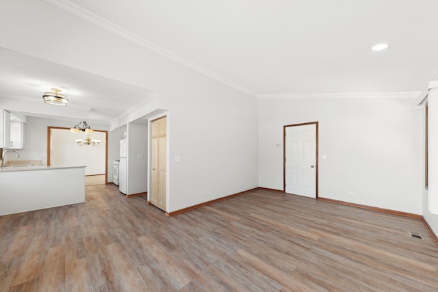 empty room featuring sink, crown molding, a chandelier, and light wood-type flooring