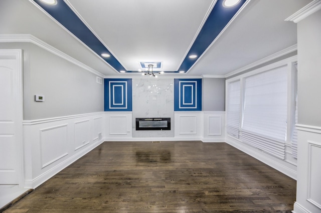 interior space featuring a raised ceiling, crown molding, dark wood-type flooring, and a large fireplace