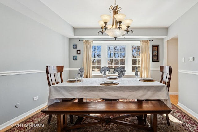 dining room featuring a chandelier, wood finished floors, and baseboards