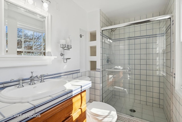 full bath with vanity, a shower stall, and toilet