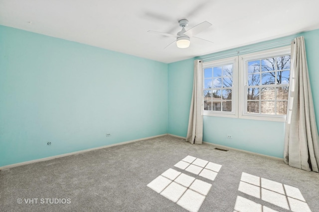 carpeted spare room with baseboards, visible vents, and a ceiling fan