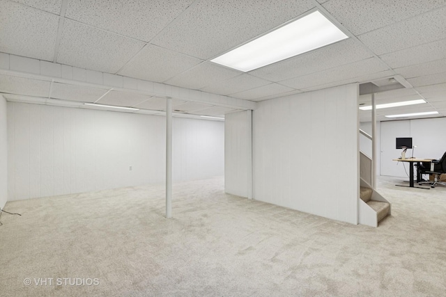 finished basement with stairway, a drop ceiling, and carpet flooring