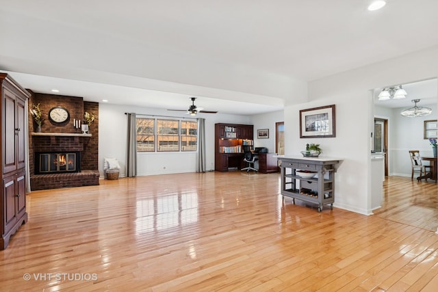 living area with light wood-type flooring, a brick fireplace, and baseboards