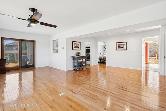 unfurnished living room with recessed lighting, light wood-type flooring, and baseboards