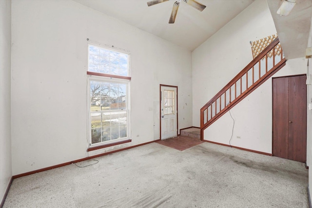 carpeted entryway with a towering ceiling and ceiling fan