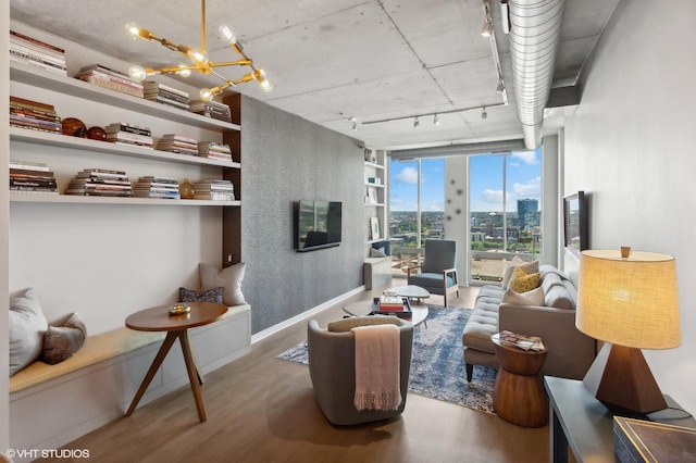 living room featuring wood-type flooring, rail lighting, a chandelier, and a wall of windows