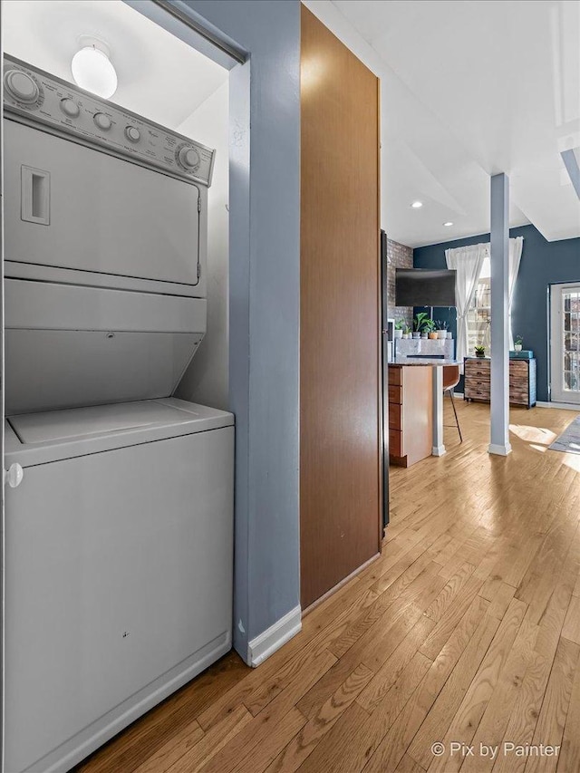 laundry area featuring stacked washer and dryer and light wood-type flooring