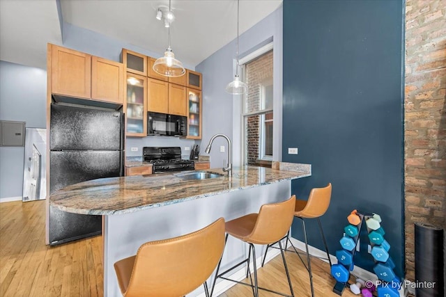 kitchen with sink, dark stone countertops, hanging light fixtures, black appliances, and kitchen peninsula