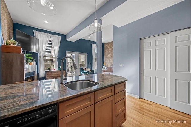 kitchen with dishwasher, sink, dark stone countertops, hanging light fixtures, and light hardwood / wood-style floors