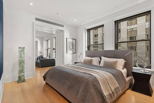 bedroom featuring ornamental molding and light wood-type flooring