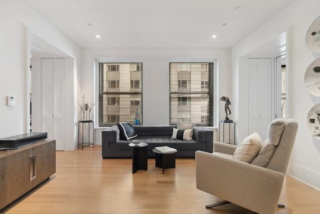 living room with plenty of natural light, ornamental molding, and light wood-type flooring