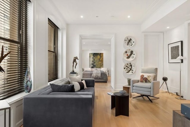 sitting room with crown molding and light hardwood / wood-style flooring