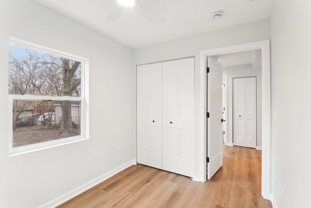 unfurnished bedroom featuring light wood finished floors, a closet, a ceiling fan, and baseboards