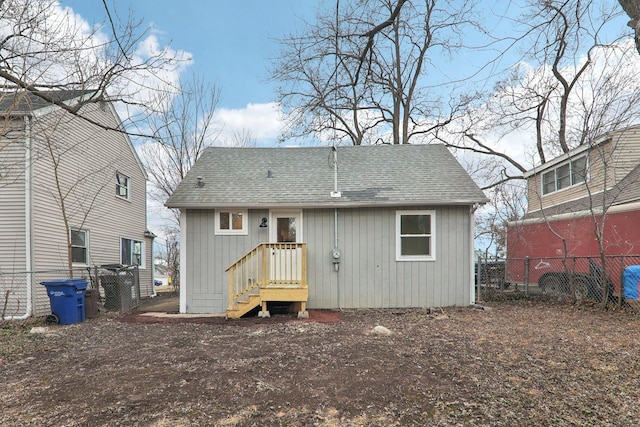 back of property with roof with shingles and fence