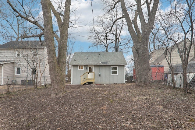 back of property with roof with shingles and fence