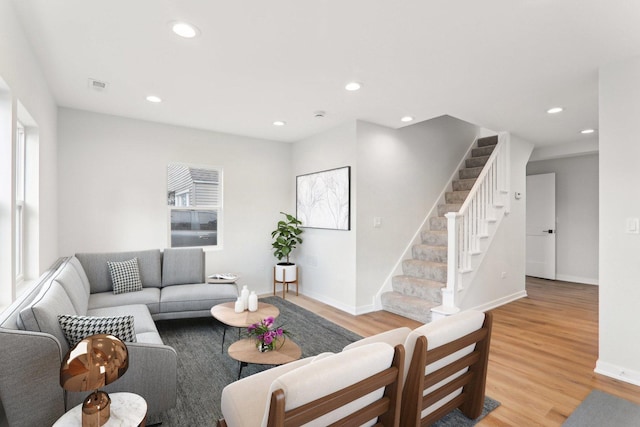 living area with light wood finished floors, recessed lighting, visible vents, baseboards, and stairs