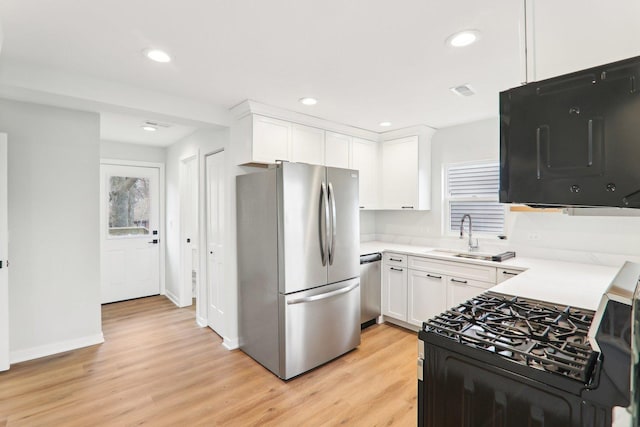 kitchen featuring stainless steel appliances, light wood-type flooring, white cabinets, and a sink