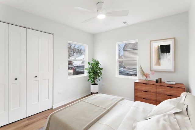 bedroom with ceiling fan, visible vents, baseboards, a closet, and light wood finished floors