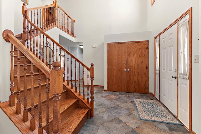 foyer entrance featuring a towering ceiling, stone finish flooring, and baseboards