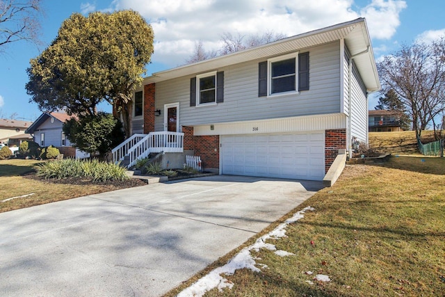 split foyer home featuring a garage, a front yard, brick siding, and driveway