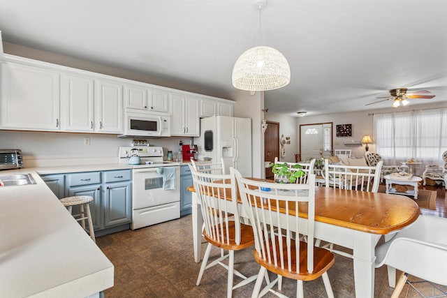 kitchen with white appliances, blue cabinets, light countertops, white cabinetry, and pendant lighting