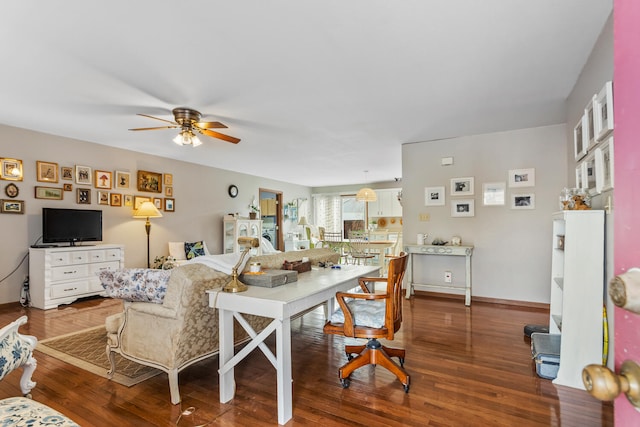 living area with wood finished floors, a ceiling fan, and baseboards