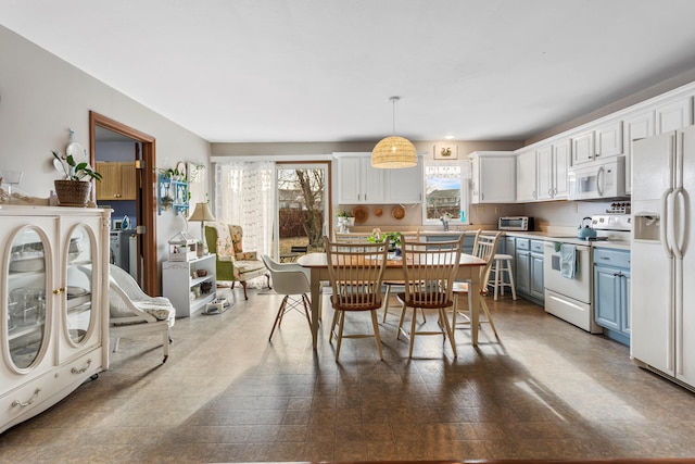 kitchen with a toaster, white appliances, white cabinets, light countertops, and pendant lighting