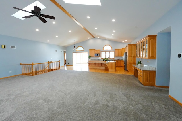 kitchen featuring a kitchen island, visible vents, open floor plan, appliances with stainless steel finishes, and glass insert cabinets