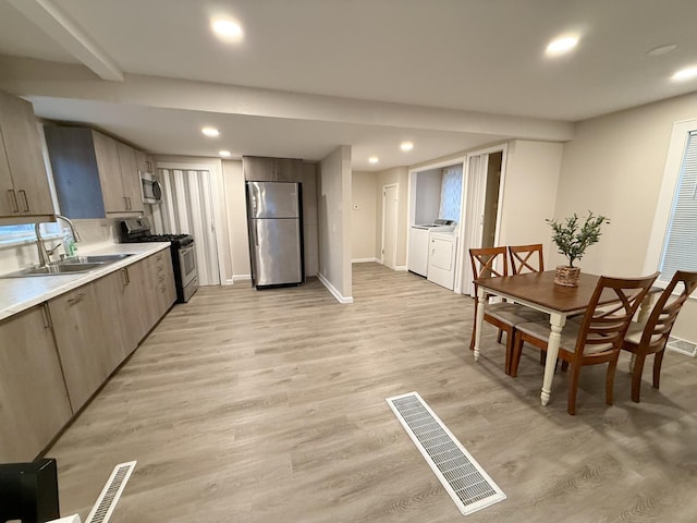 kitchen with separate washer and dryer, sink, light wood-type flooring, and appliances with stainless steel finishes