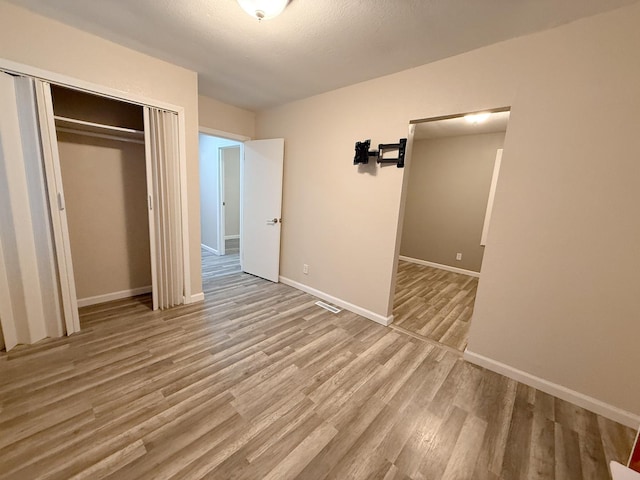 unfurnished bedroom with a closet and light wood-type flooring