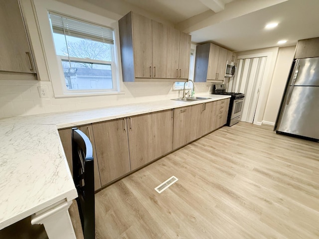 kitchen featuring sink, appliances with stainless steel finishes, tasteful backsplash, light hardwood / wood-style floors, and light brown cabinetry