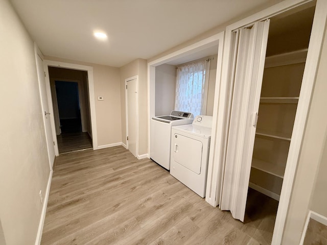 clothes washing area featuring separate washer and dryer and light hardwood / wood-style floors