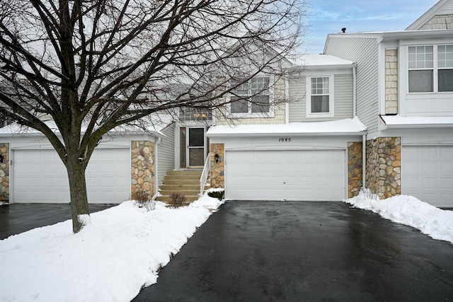 view of front facade featuring stone siding, aphalt driveway, and an attached garage