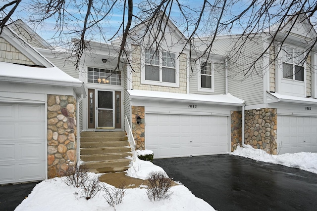 multi unit property with a garage, driveway, and stone siding