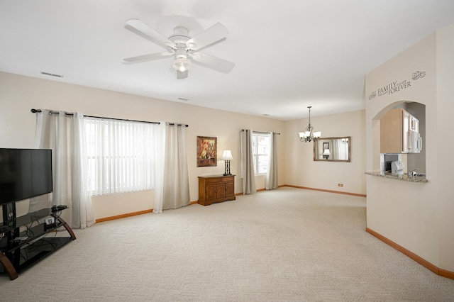 unfurnished living room featuring ceiling fan with notable chandelier, light colored carpet, visible vents, and baseboards