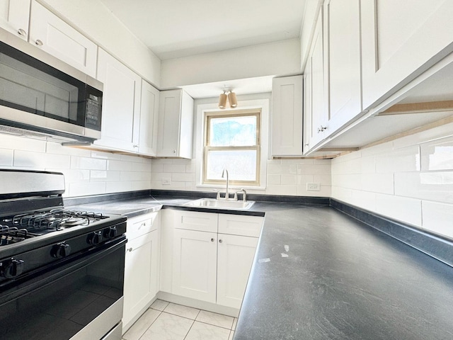 kitchen featuring dark countertops, stainless steel microwave, tasteful backsplash, range with gas stovetop, and a sink