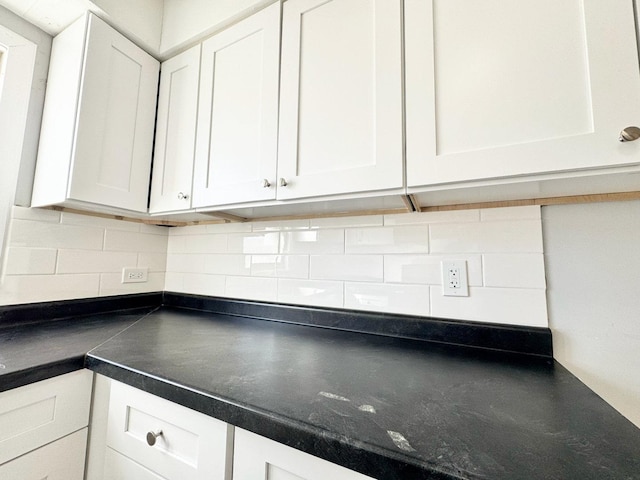 kitchen with decorative backsplash, dark countertops, and white cabinetry